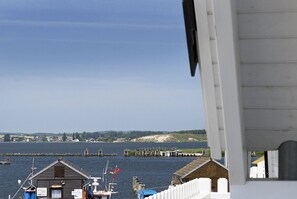 Een uitzicht op de kust met een houten gebouw, een steiger en een heldere lucht.