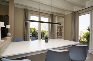A modern dining area with a white table, blue chairs, and a potted plant.