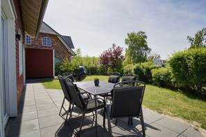 A patio with a table and chairs, a barbecue grill, and a brick house in the background. - ButjeButje Vacation Home - Swedish-style house by the marina, private sauna, adventure pool - (Gager)