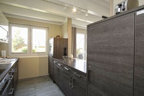 A modern kitchen with dark wood cabinets, a stainless steel range hood, and a window providing natural light.