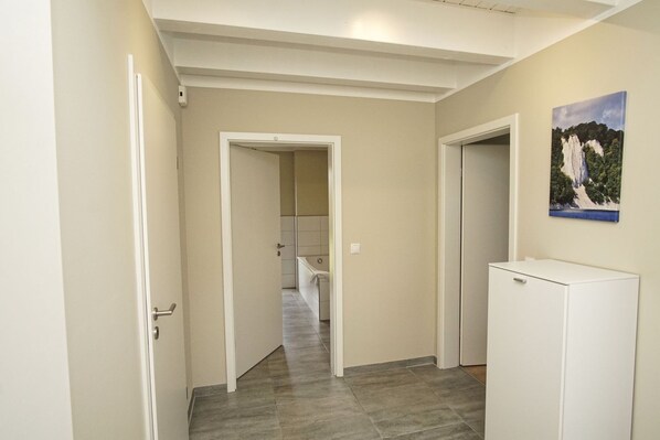 A hallway with a door leading to a bathroom, a refrigerator, and a painting on the wall.