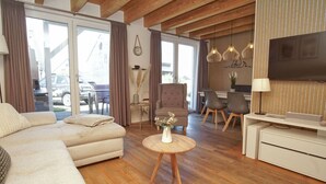 Ein modernes Wohnzimmer mit einer Couch, einem runden Couchtisch, einem Fernseher und einem Essbereich mit Stühlen und einem Tisch.