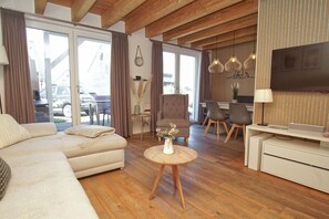 Una sala de estar moderna con un sofá, una mesa redonda, un televisor y un comedor con sillas y una mesa.