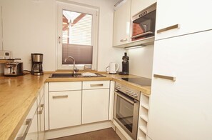 Una cucina compatta con lavello, fornello e macchina da caffè.