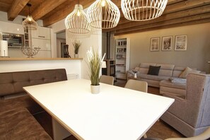 A modern kitchen with white cabinets, a dining table, and a sofa in a living area.