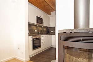 A modern kitchen with white cabinets, a built-in oven, a microwave, and a stainless steel range hood. - Vacation home near the harbor with a terrace and ocean view - Ferienhaus TimpeTe Backbord - (Gager)