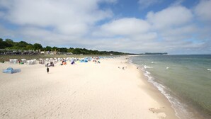 Une plage avec des tentes et des gens, un ciel dégagé et une mer calme.