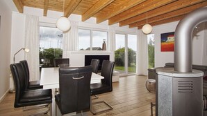 Une cuisine moderne dotée d’un grand îlot central, de poutres en bois au plafond et offrant une vue sur l’extérieur.