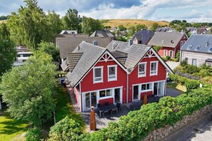 A red house with a sloped roof, a front porch, and a garden area with a table and chairs. - Vacation home close to the harbor with terrace and sea view - Holiday home TimpeTe Starboard (Gager)