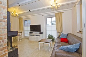 A living room with a fireplace, a television, a sofa, and a dining area with chairs.
