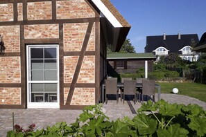 Ein Ziegelhaus mit einem großen Fenster und einer Terrasse mit Gartenmöbeln.