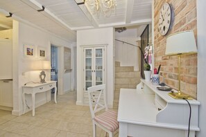 A well-lit, spacious room with a white desk, chair, and a small table with a lamp. A clock is visible on the wall, and there is a door leading to another room. - Min Hüsung Vacation Home - A vacation home in an idyllic setting, with a terrace and garden (Gager)