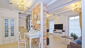 Una sala de estar moderna con un escritorio blanco, un televisor y un sofá.