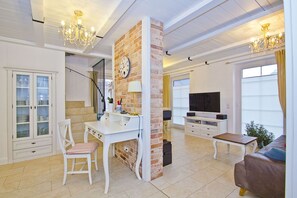 Ein modernes Wohnzimmer mit weißem Schreibtisch, Fernseher und einer Couch.