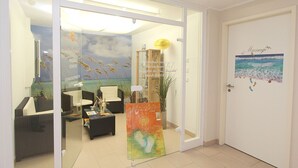 A reception area with a glass door, a reception desk, a sofa, a coffee table, and a painting on the wall. - Near the beach, vacation apartment with sauna and swimming pool - Strandr.BaabeFeWo1.29 (Baabe)