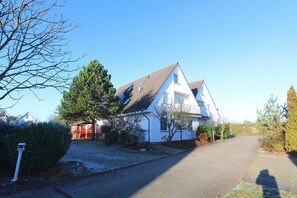 Une maison à deux étages avec un toit en pente, un garage rouge et une allée pavée.