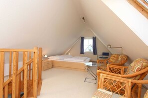 A small, cozy attic bedroom with a wooden bed, a small table, and wicker chairs. - Morgensonne Apartment - Apartment in a quiet location with a balcony - (Breege)