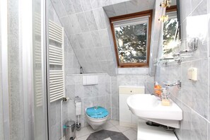 A bathroom with a toilet, sink, and window. - Apartment Morgensonne - Apartment in a quiet location with balcony - (Breege)