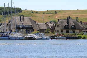 Un village côtier avec des maisons traditionnelles aux toits de chaume et des bateaux amarrés le long du rivage.