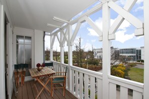 A wooden deck with a table and chairs, white railings, and a view of buildings and trees. - F-1044 Ferienwohnung Having - Ferienwohnung Having F-1044 Wohnung 315 (Sellin)