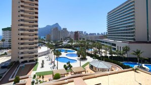 Hotel alto com várias varandas, área de piscina central com diversas piscinas e vista para uma montanha ao fundo.