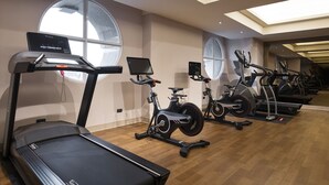 Uma academia com esteiras, bicicletas ergométricas e elípticos.