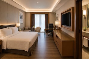 A hotel room with a large bed, a desk, a TV, and a bathroom with a mirror and towel rack. - Hamp Court Palace Taipei (Taipei)