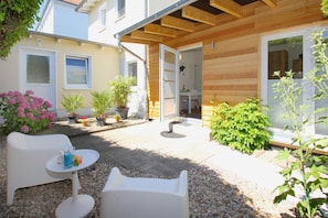 A patio area with outdoor furniture, potted plants, and a wooden pergola.