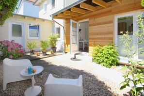 A patio area with outdoor furniture, potted plants, and a wooden pergola.