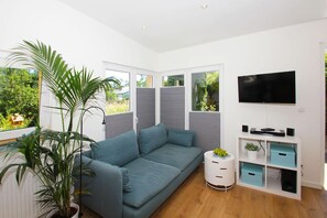 Un salon moderne avec un canapé, un téléviseur et un meuble de rangement blanc.