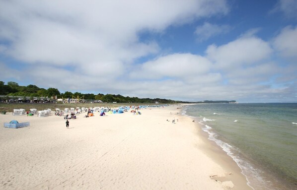 Une vaste plage de sable où l’on voit des tentes et des gens.
