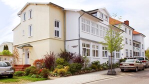 Um edifício residencial de dois andares com fachada bege e detalhes brancos.