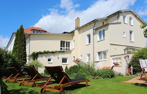 A two-story building with a garden area featuring sun loungers and a small playhouse. - Villa Elise F-1093 Apartment 02 - F-1093 Villa Elise (Göhren)