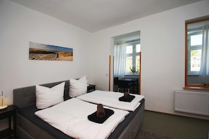 A hotel room with two beds, a painting on the wall, a window, and a view of the outside.