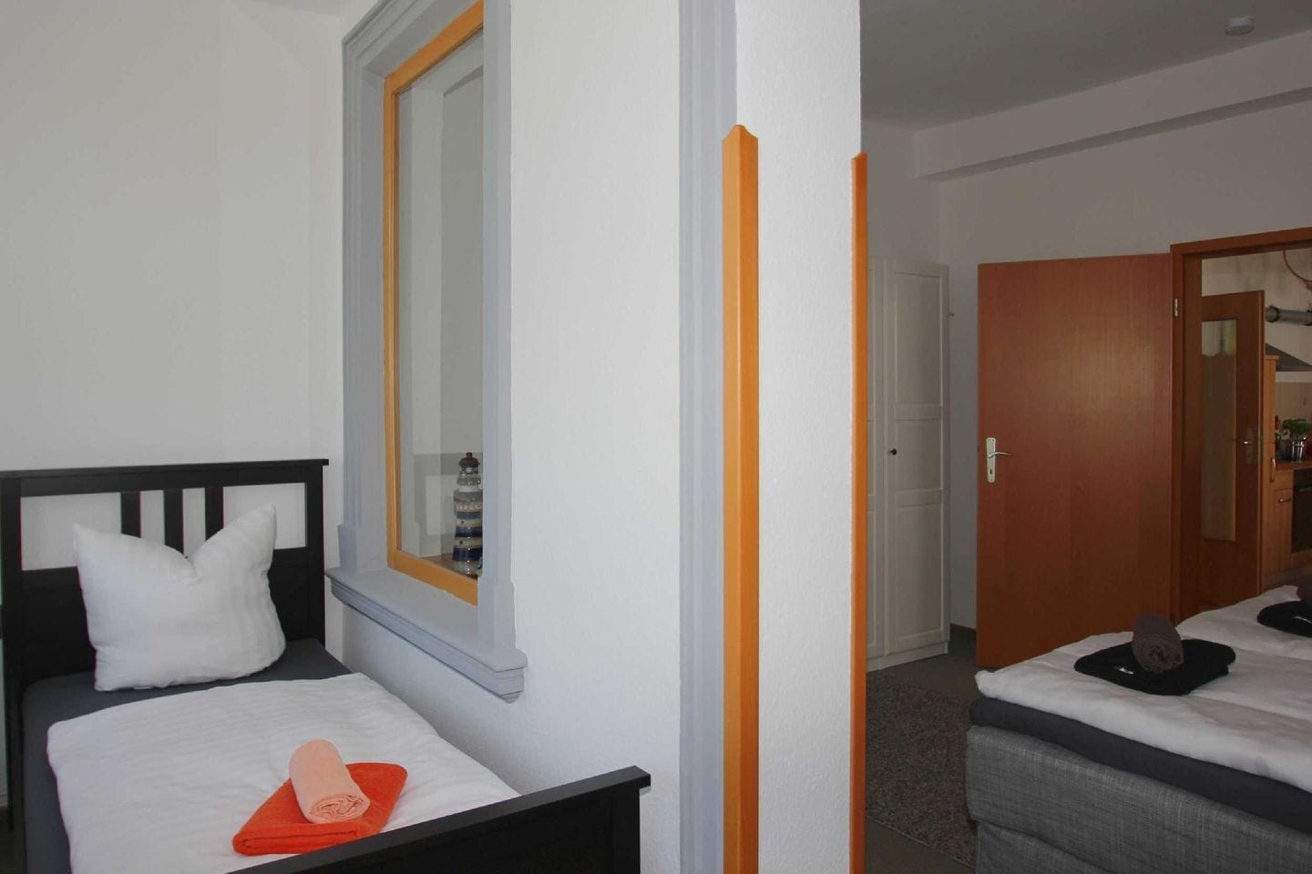 A hotel room with a single bed, a window with a view, and a door leading to another room.