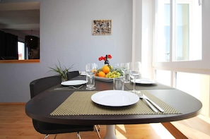 A dining table set with plates, glasses, and a fruit bowl.