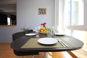 Una mesa lista con platos, vasos y un frutero.