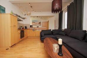 A modern living room with a dark-colored sofa, a wooden coffee table, and a lit candle.
