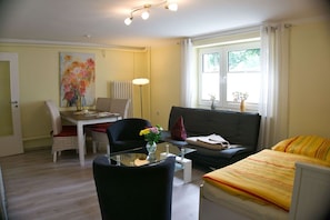 Une pièce de taille modeste comprenant un lit, un canapé, une table à manger avec des chaises et une grande fenêtre.