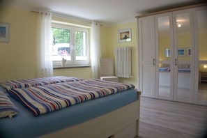 Un dormitorio con dos camas, una ventana con cortinas, un radiador y un armario.