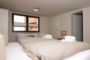 A hotel room with a large bed, a bedside table, a chair, and a window with blinds. - Haus Maiglöckchen F-1016 Wohnung 02 - F-1016 Haus Maiglöckchen (Göhren)