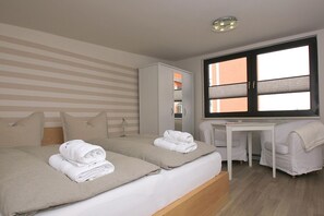 Habitación de hotel con dos camas, un escritorio y un armario.