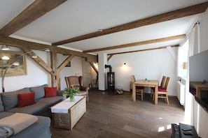 Una sala de estar acogedora con sofá, sillas, una mesa de comedor y una chimenea.