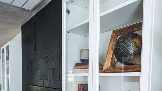 Una sala de estar moderna con chimenea, muebles blancos y una gran planta en maceta.
