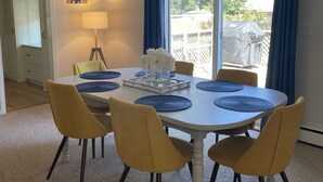Un comedor con una mesa redonda, sillas amarillas y un florero con flores.