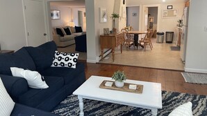 Una sala de estar con un sofá azul oscuro, una mesa de centro blanca y una alfombra estampada.