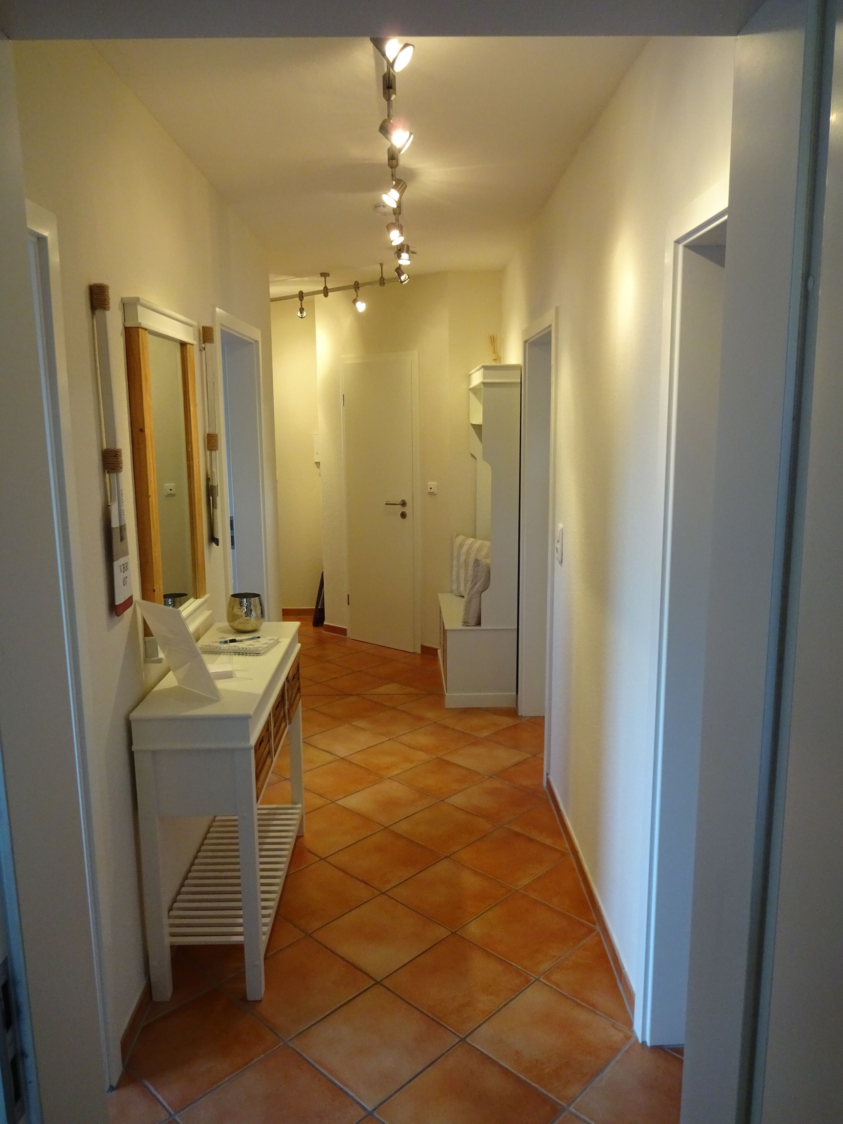 A hallway with a white vanity, a mirror, and a towel rack.