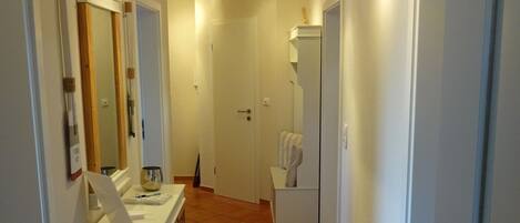 A hallway with a white vanity, a mirror, and a towel rack.