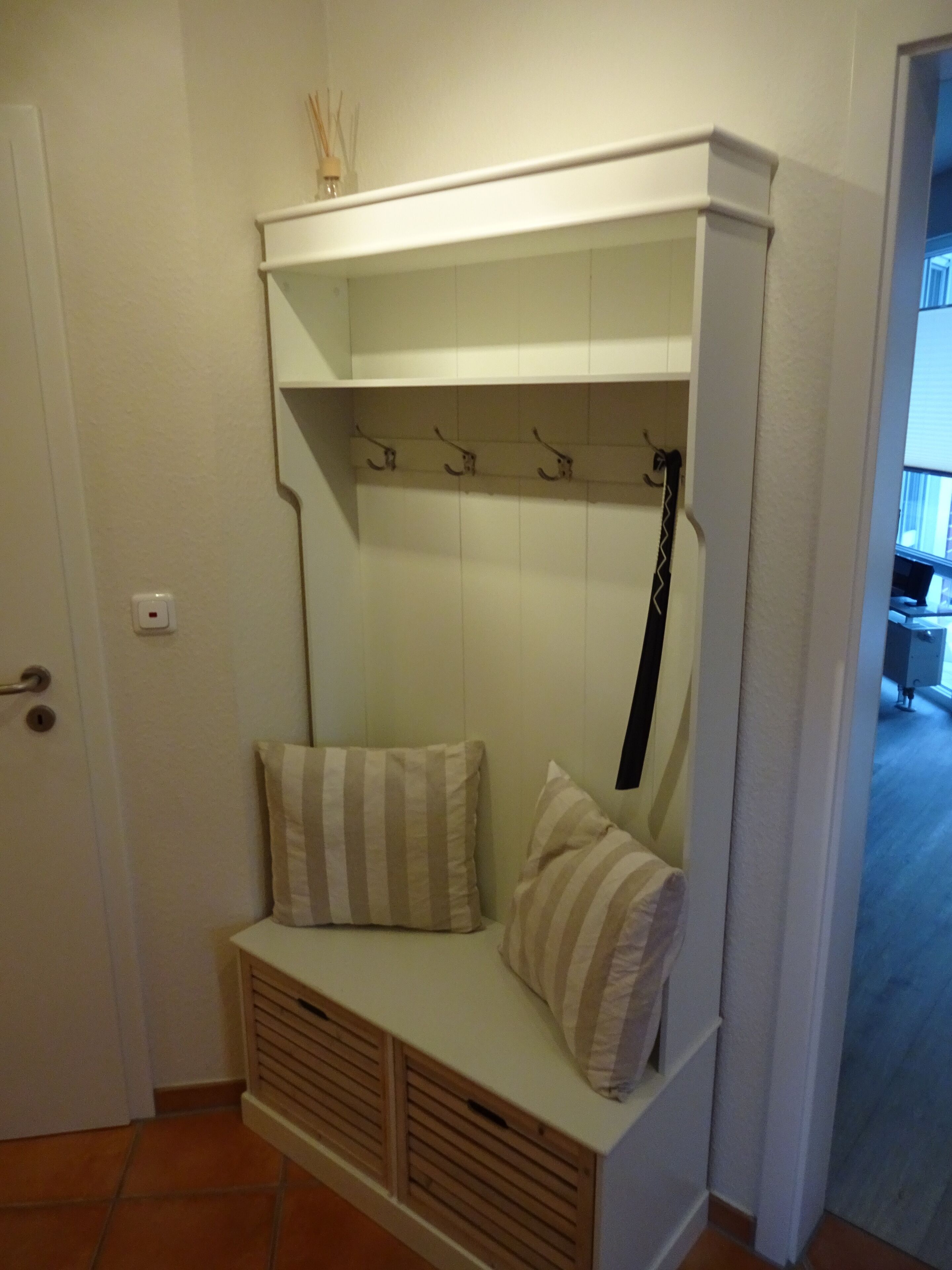 Un petit espace de repos clos, comprenant un banc, deux coussins et un porte-manteau.