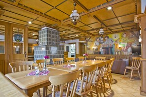 Un interior de restaurante con mesas y sillas de madera, una chimenea de piedra y un mural en la pared.